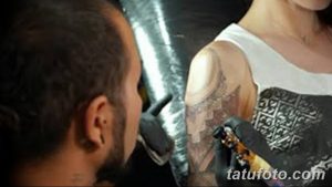 Фото процесса нанесения геометрической татуировки на плечо, демонстрирующее работу мастера и сложность узора.